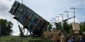 Піднята пускова установка Patriot під маскувальною сіткою з антенами та військовими